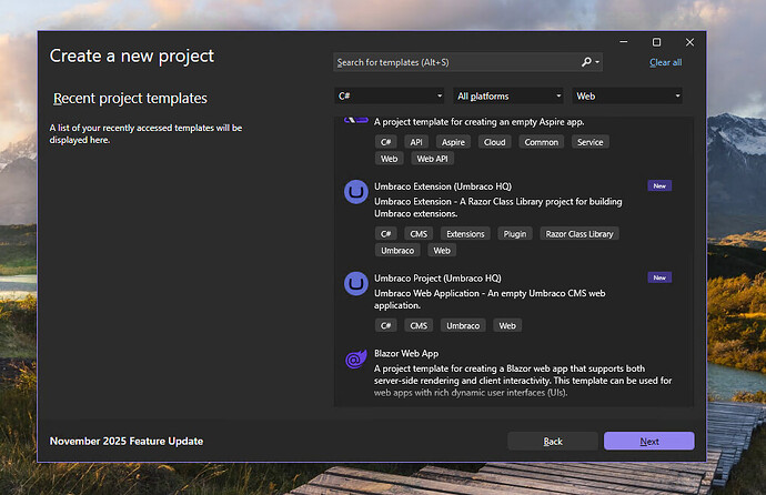 The "Create a new project" window in a software application displays various project templates, including Umbraco Extension and Blazor Web App, against a backdrop of a scenic mountain landscape, and mentions a "November 2025 Feature Update". (Captioned by AI)